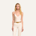 Woman with long blonde hair wearing the Lexi Silk Camisole in pearl white, paired with matching beige pants and a tan belt, standing against an off-white background.