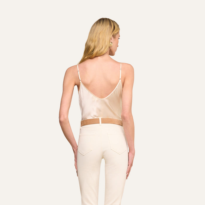 Woman with long blonde hair shown from the back, wearing the Lexi Silk Camisole in pearl white with thin straps and off-white pants, standing against a plain light background.