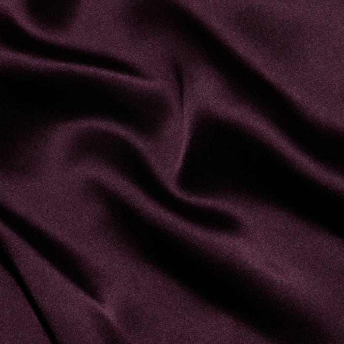 Luxurious deep purple satin with soft, smooth folds and a delicate sheen, forming gentle waves and shadows across the surface—evocative of the Lexi Silk Camisole.