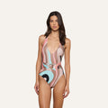 A woman wears the Lisa Plunge One-Piece Swimsuit, featuring an abstract swirl print, a plunging neckline, ruched waistband, and retro pastel hues, standing against a plain light background.
