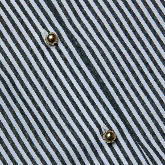 Close-up of the Lorena Cover-Up Shirt, showcasing its cotton poplin fabric with black and white diagonal stripes and two gold buttons sewn in a vertical line. The visible texture and stitching around the buttons highlight the crisp finish reminiscent of a classic resort shirt.