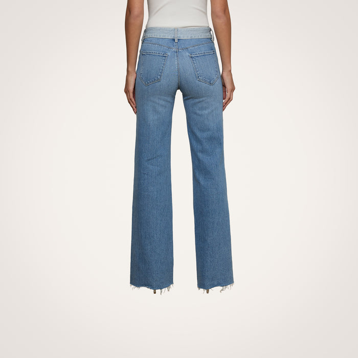 A person shown from the back is wearing Louane Wide-Leg Flare Jeans in a high-rise, light blue wash with frayed hems, paired with a white top.