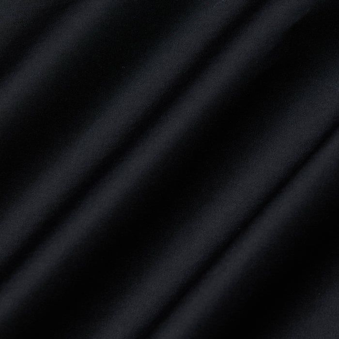 Close-up of the Lowen Pant’s black poplin fabric, featuring diagonal, soft shadows and a subtle texture that creates a striped pattern across the surface.