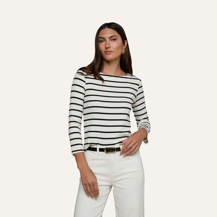 Woman wearing the Lucille Striped Boatneck Top paired with white pants and a black belt, posing against a plain light background.