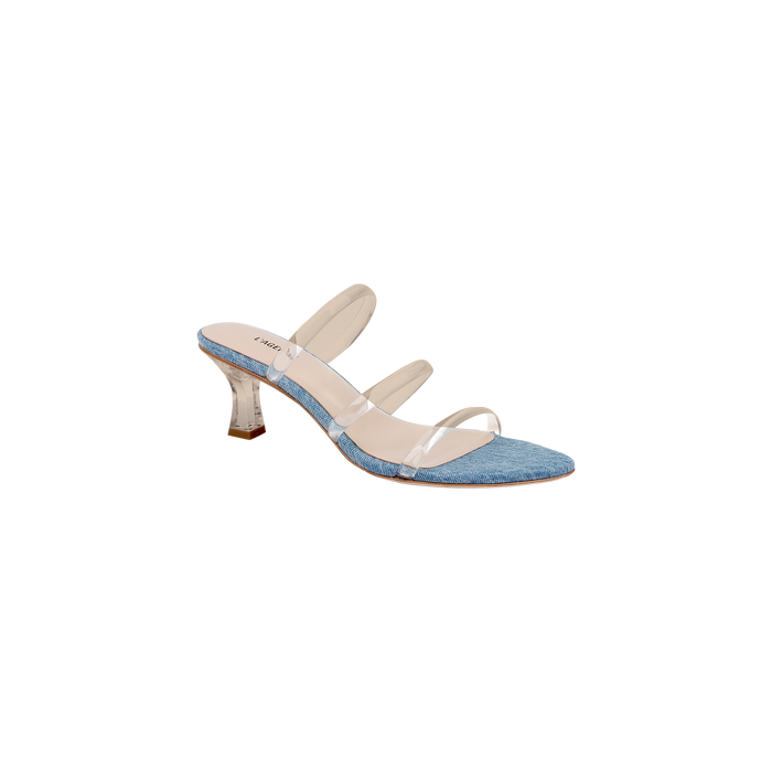 The Ludovica Kitten-Heel Sandal is a fashionable denim mule featuring a blue denim sole, three clear vinyl straps across the foot, and a translucent curved heel, displayed on a white background.