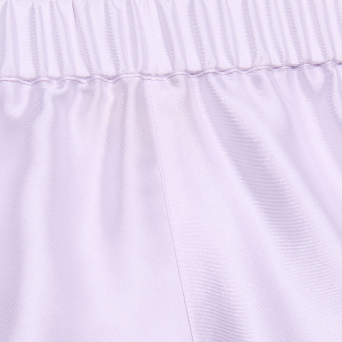 Close-up of the Maela Short in light purple, featuring a shiny poly twill fabric, an elastic waistband, and a visible vertical center seam—ideal for comfortable pull-on wear.