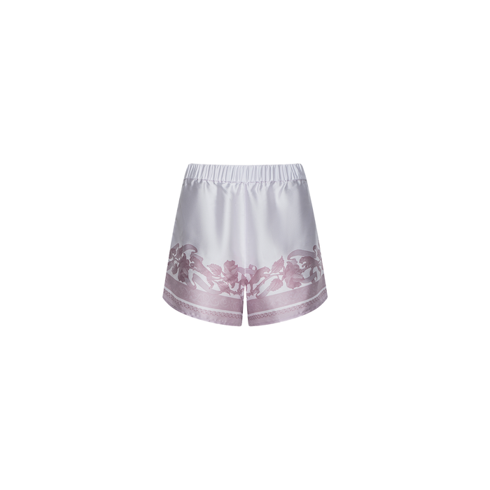The Maela Short is a satin pull-on style with an elastic waistband, crafted in shiny white fabric and accented with a pink floral pattern along the hem, shown against a plain white background.