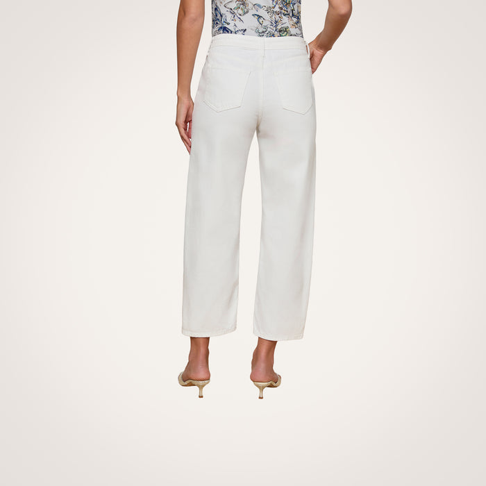 A person wearing the Mallis Bow-Leg Jean in white and beige heels stands with their back to the camera. The top part of a patterned shirt is visible, set against a plain, light-colored background.