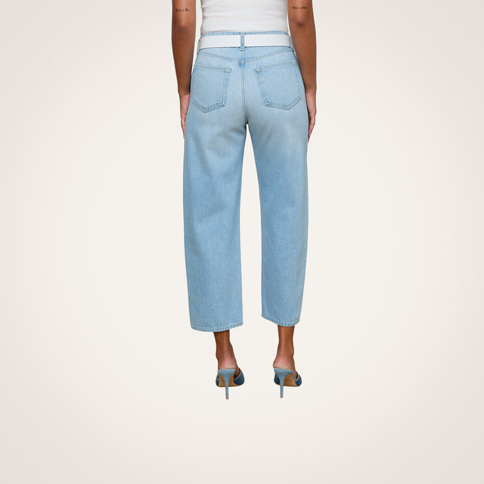 A person wearing the Mallis Bow-Leg Jean in a light wash and high heels stands with their back to the camera against a plain white background.