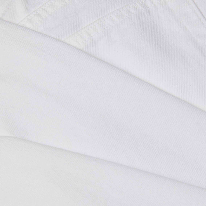 Close-up of overlapping pieces of white all-cotton denim fabric from the Mallis Bow-Leg Jean, showcasing visible stitching and texture.