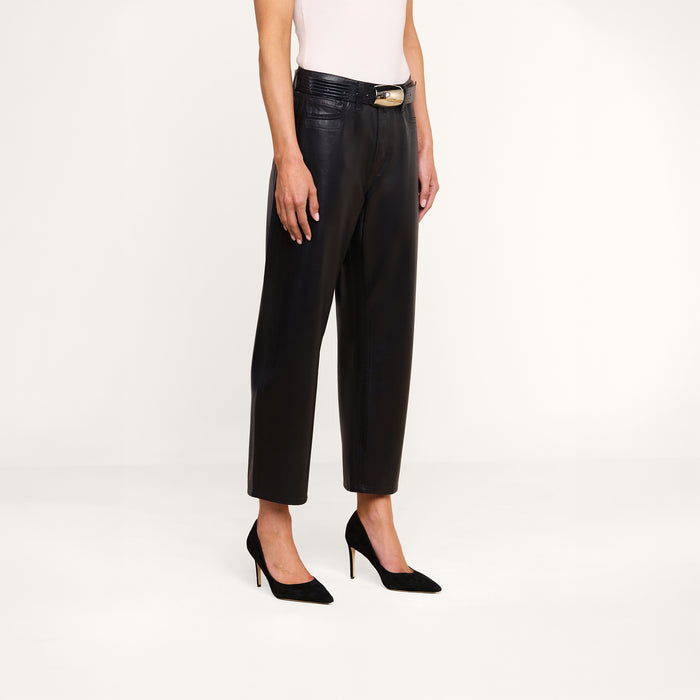 Person wearing the Mallis Coated Bow-Leg Jean, styled with a black belt and black pointed-toe high heels, standing against a plain white background. Upper body is partially out of frame.