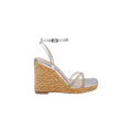The Malone Wedge Espadrille is a silver sandal with a braided raffia wedge heel, ankle strap, minimalist toe straps, and a square toe, shown in side profile on a white background.