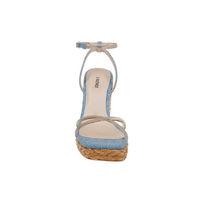 Front view of the Malone Wedge Espadrille, featuring a denim blue upper, beige ankle strap, tan sole, and a woven raffia wedge platform heel in a bohemian espadrille design, displayed on a plain white background.