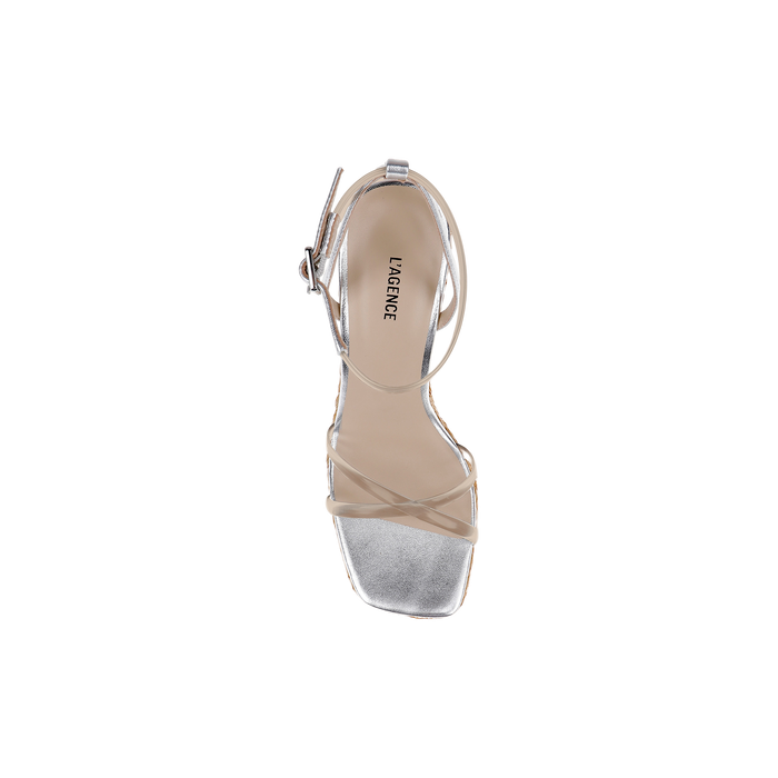 A single Malone Wedge Espadrille in silver is shown from above on a plain white background, featuring an open square toe and thin ankle and toe straps. The insole displays “LAGENCE” printed in black text.