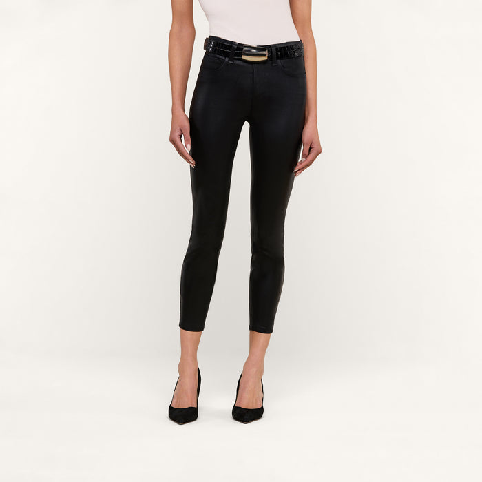 A person wearing a white sleeveless top, black high-heeled shoes, and the Margot Coated Cropped Skinny Jean with a black belt, standing against a plain white background.