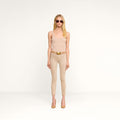 A woman stands against a plain white background wearing sunglasses, a beige tank top, beige heels, and the Margot Cropped Skinny Jean featuring a contoured waistband.