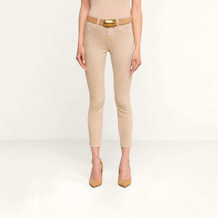 A person stands facing forward, wearing the Margot Cropped Skinny Jean—a beige high-rise skinny jean with a contoured waistband—paired with a beige belt, nude heels, and a beige top against a plain white background.