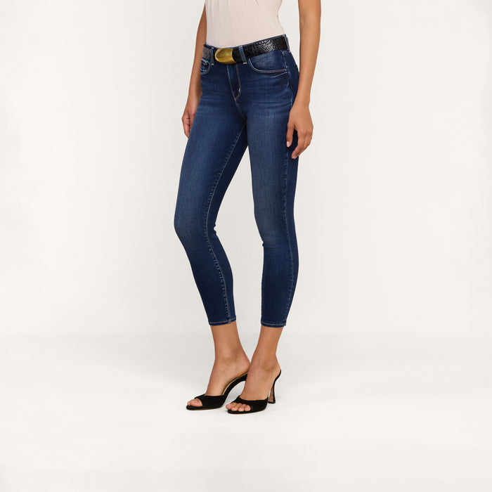 A woman models the Margot Cropped Skinny Jean, crafted from premium stretch denim, styled with a black belt and black open-toe heels. The photo is taken against a plain white background, showing her from shoulders to feet.