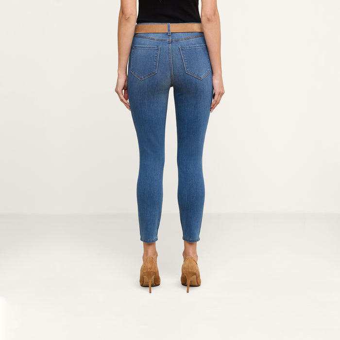 A person is shown from behind wearing a black top, the Margot Cropped Skinny Jean in a vintage wash high-rise style, and tan high-heeled shoes against a plain light background.