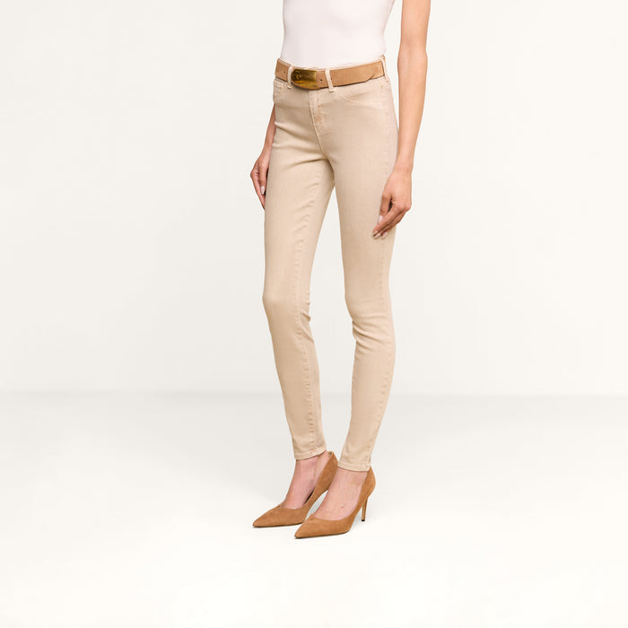 Wearing the Marguerite Skinny Jean in beige, crafted from high-recovery fabric, paired with a brown belt and brown high-heeled shoes, the person stands against a plain white background. Their upper body and face are not visible.