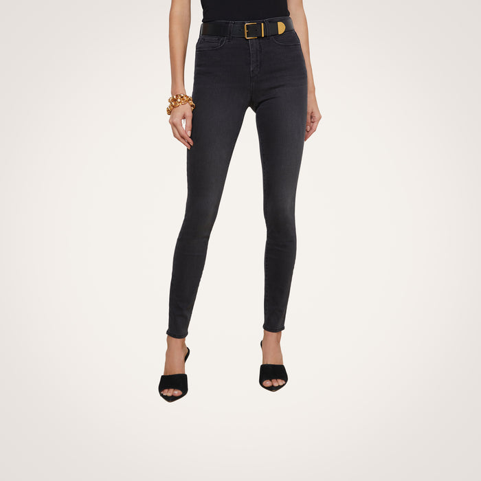 A person wearing the Marguerite Skinny Jean with a belt, black open-toe heels, and a chunky gold bracelet, standing against a plain white background.