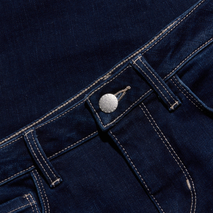 Close-up of the waistband and front pocket of dark blue denim jeans, featuring a silver button, classic belt loops, and visible white stitching for a timeless look.