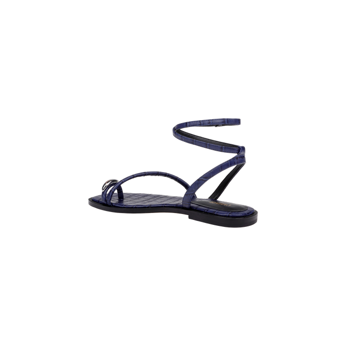 The Mariana Leather Sandal, a navy croc-embossed design featuring thin straps and an ankle tie flat strap that wraps around the ankle, is displayed in a side view against a plain white background.