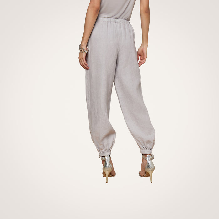 A person is shown from the back against a plain white background wearing the Mariko Linen Jogger in light gray with elastic cuffs and high-heeled sandals.