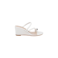The Maritza Wedge Sandal is a white wedge sandal with two slim straps and a decorative silver bead near the toe. It features an open toe, a comfortable walkable wedge, and a low wooden sole.