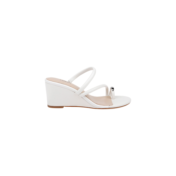 The Maritza Wedge Sandal is a white wedge sandal with two slim straps and a decorative silver bead near the toe. It features an open toe, a comfortable walkable wedge, and a low wooden sole.