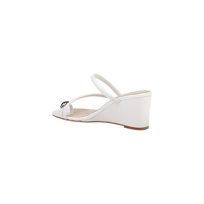 The Maritza Wedge Sandal features a white design with an open toe, two slender straps, and a subtle decorative accent on the front strap. Crafted for both comfort and style, it’s set on a walkable wedge with a tan sole, shown against a plain white background.