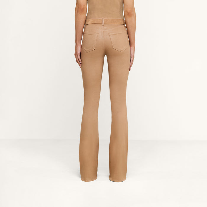 A person standing, facing away, wears the Marty Coated Flare Jean in tan with a matching top against a plain white background.