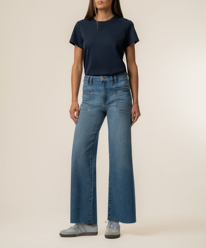 Woman wearing navy short-sleeve t-shirt and high-rise wide-leg jeans in light blue denim with patch pockets.