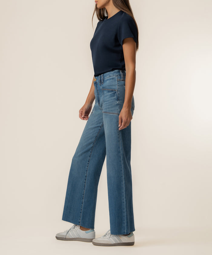 Woman wearing navy short-sleeve t-shirt and light blue high-rise wide-leg jeans with white sneakers.