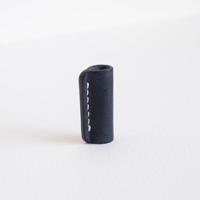Midnight leather Lumos grip and rollstop standing upright on a white background, showing hand-stitched detail.