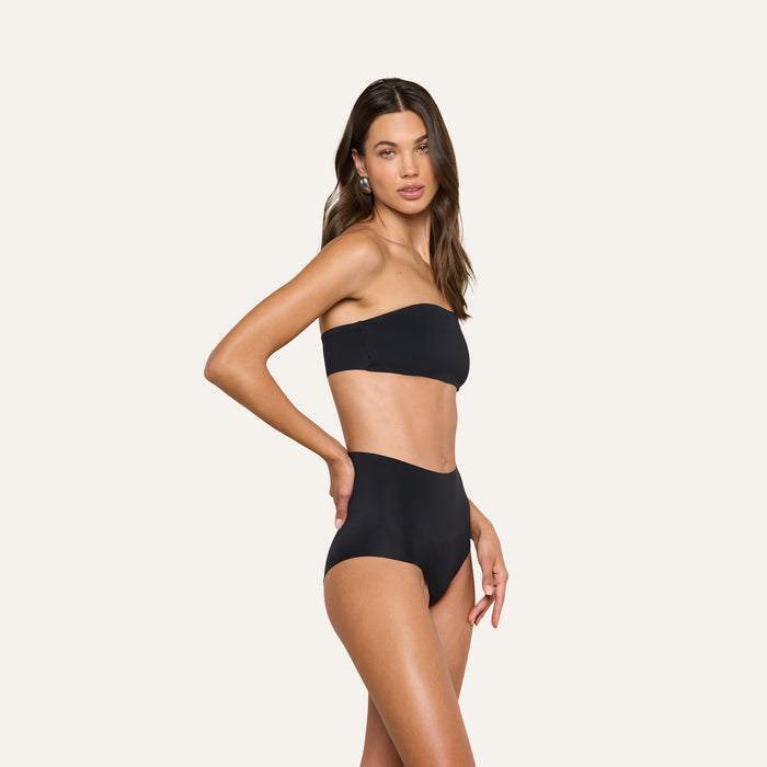 A woman poses in the Mietta Knit Bandeau Top and high-waisted bikini bottoms against a plain light background.