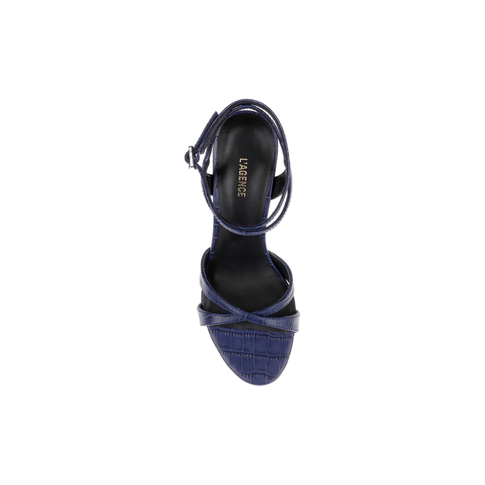 A top view of the Miranda Leather Sandal showcases its navy blue, textured design and ankle-wrap strap, with LAGREVE branding on the black insole, displayed on a plain white background—ideal for complementing evening gowns.