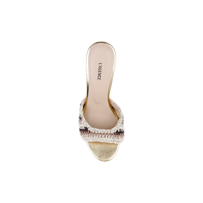 The Moyes Crochet Sandal is a gold open-toe heeled sandal featuring a sculpted heel and a woven cream and brown strap, shown from above on a white background. The insole is labeled LAGENCE.
