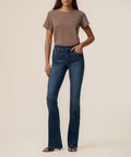 Woman wearing a taupe t-shirt and dark blue bootcut jeans with high rise waistband.