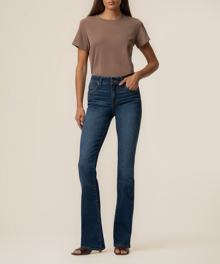 Woman wearing a taupe t-shirt and dark blue bootcut jeans with high rise waistband.