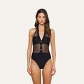 A woman stands against a plain light background wearing the Natalya Collared One-Piece Swimsuit—a chic French design in black mesh featuring a plunging neckline, mesh panels, three front buttons, and UPF 50 protection.