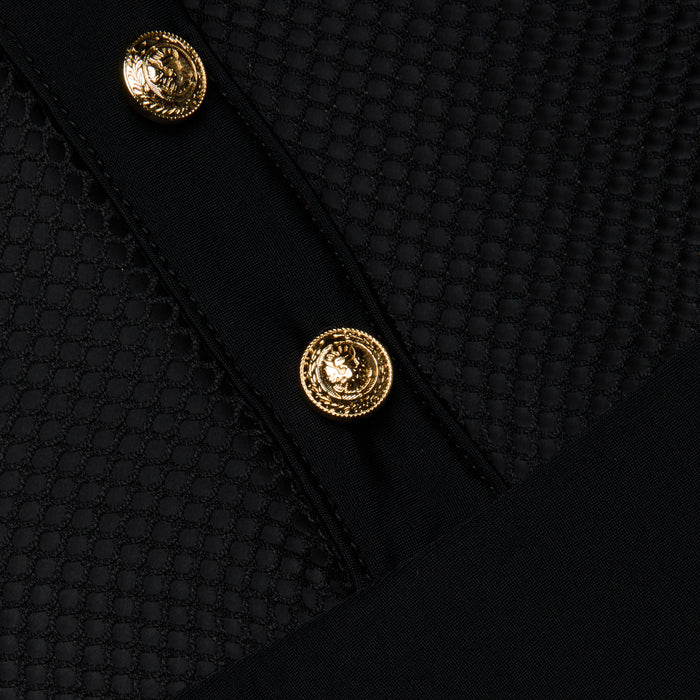 A close-up of the Natalya Collared One-Piece Swimsuit in black showcases its textured fabric with two gold decorative buttons, featuring a mesh-like hexagonal pattern reminiscent of a mesh one piece and smooth black panels intersecting diagonally across the image.