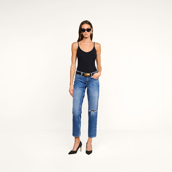 Woman wearing sunglasses, a black tank top, the Nevia Slouchy Straight-Leg Jean in a vintage-inspired blue wash with a black belt, and black high heels, standing against a plain white background.