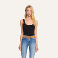 A woman with long blonde hair wears the Nica Scoopneck Bodysuit in black, paired with blue jeans and a tan belt, standing against a plain light background, facing the camera with a neutral expression and her arms relaxed by her sides.