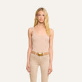 A woman with long blonde hair wears the Nica Scoopneck Bodysuit in beige, along with beige pants and a belt featuring a gold buckle, standing against a plain light background and facing forward with a neutral expression.