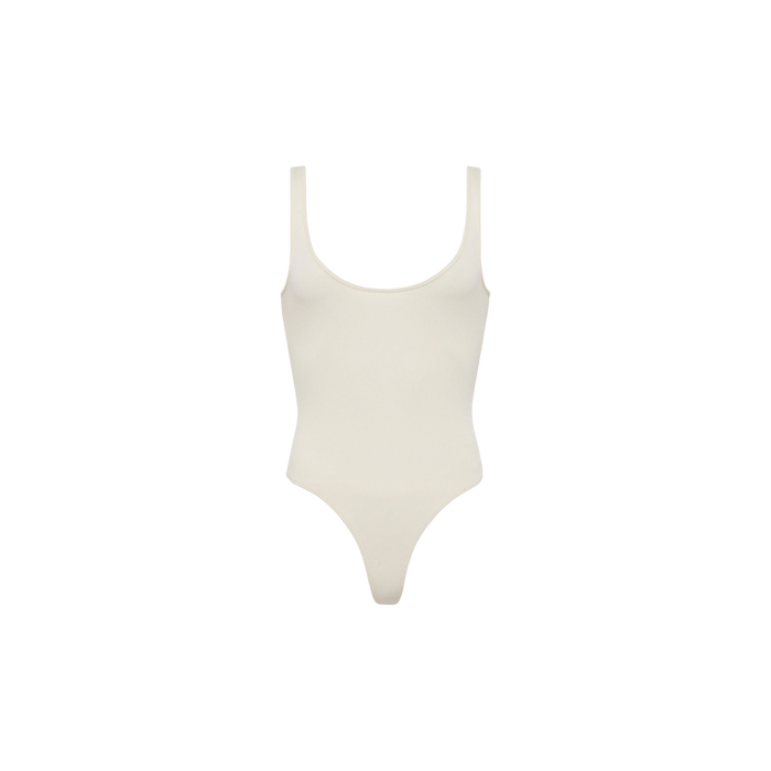 The Nica Scoopneck Bodysuit is an ivory, sleeveless piece made from stretch cotton, featuring a flattering scoop neckline and high-cut leg openings—ideal for versatile layering. Shown against a plain white background.