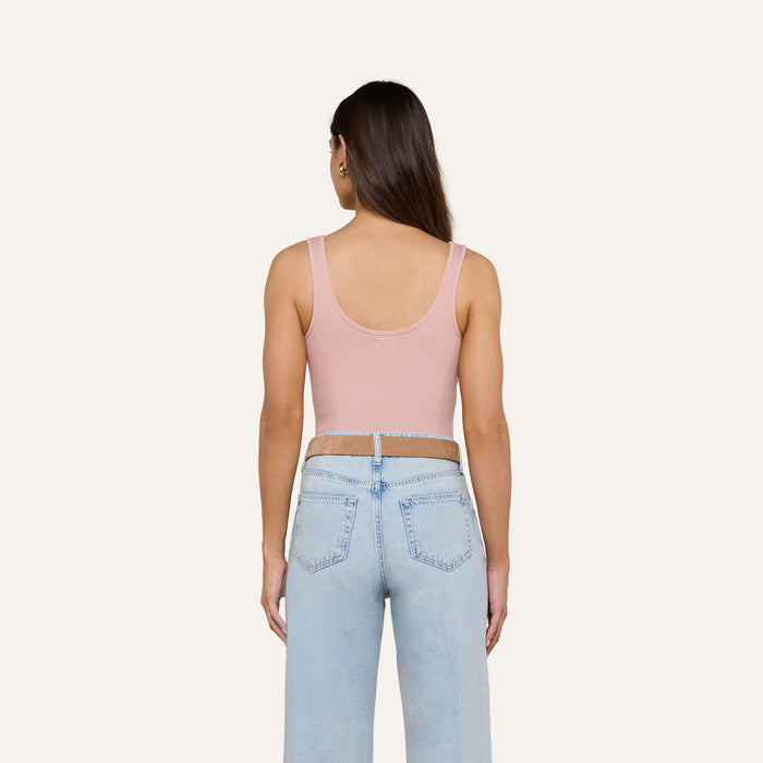 A person with long brown hair is wearing the Nica Scoopneck Bodysuit in pink and light blue sculpted-fit jeans, standing facing away against a plain background.