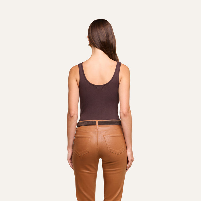 A woman stands facing away, wearing a dark brown Nica Scoopneck Bodysuit and tan pants with pockets. Her straight brown hair is down, and she is positioned against a plain light background.