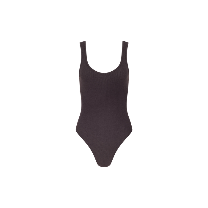 The Nica Scoopneck Bodysuit is a sleeveless, dark-toned piece featuring a scoop neckline and high-cut legs, made from stretch rib fabric and shown against a plain white background.