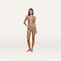 Woman standing against a plain background, exuding Parisian glamour in a black and white striped Nicole Bikini Bottom crafted from four-way stretch nylon, her arms relaxed at her sides.